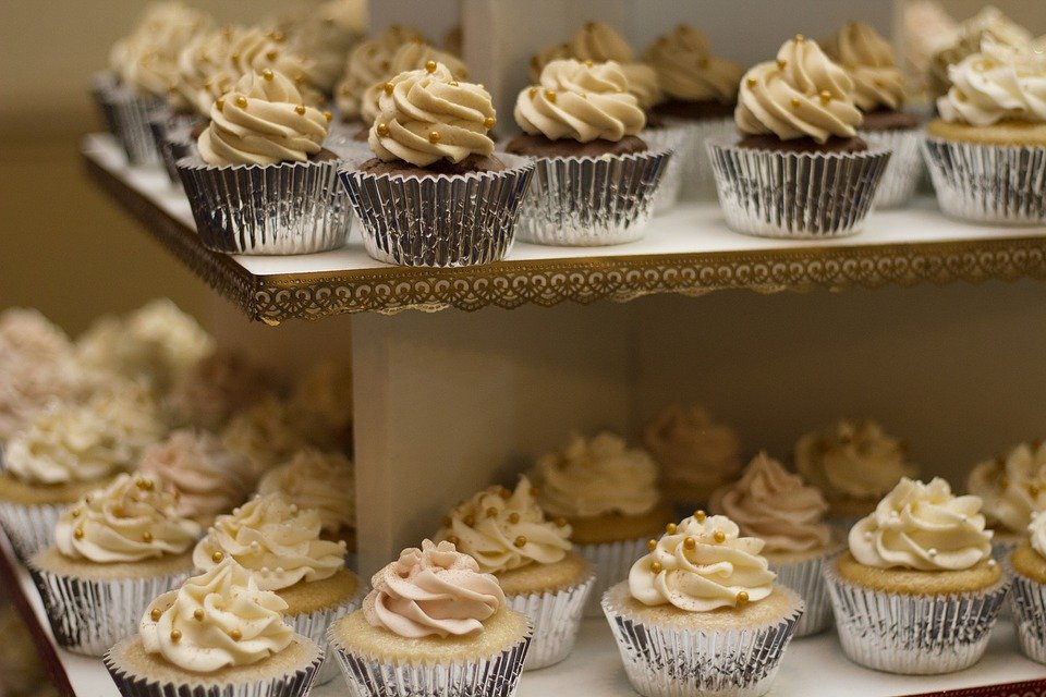 many cupcakes lined up on two sheets.